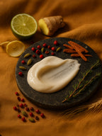 Platter with mayonnaise, garnished with herbs, spices, and vegetables on a warm-toned fabric background. Suvéra Self Care Silk Skin Body Serum on dark stone, surrounded by pink pepper, cardamom, ginger, sandalwood, lime, and vetiver.
