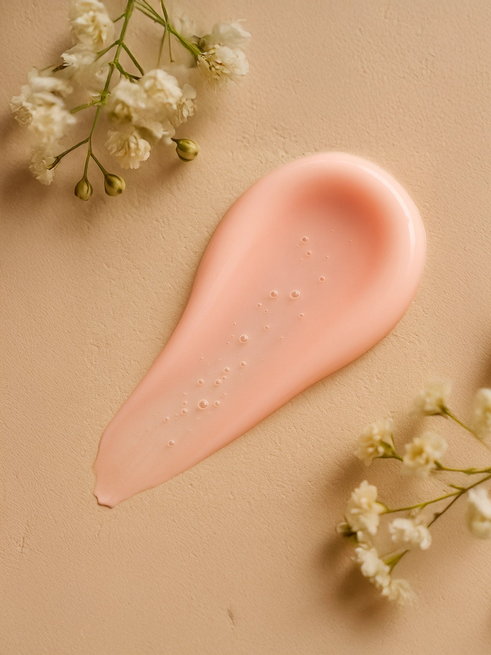 Pink cosmetic smear with small white flowers on a beige background Peptide Serum