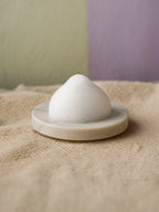 White ceramic object on a beige surface with a blurred background Purifying Mousse