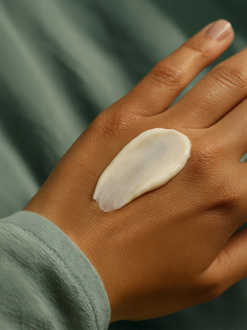 Hand applying a white cream on a blurred green background Sensitive Skin Moisturiser, Fragrance Free