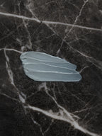 Small light blue leaf on a dark marble surface
