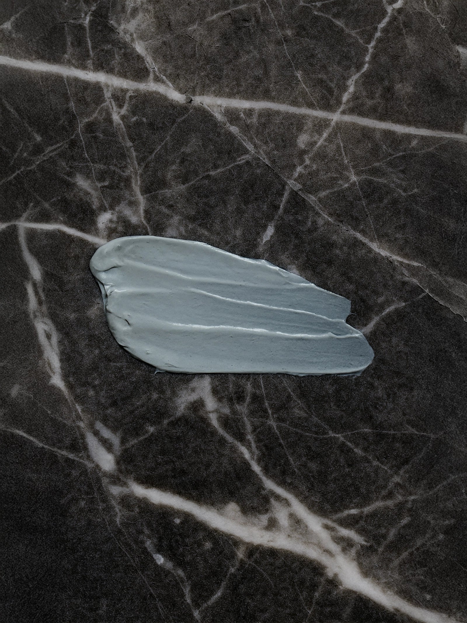 Small light blue leaf on a dark marble surface