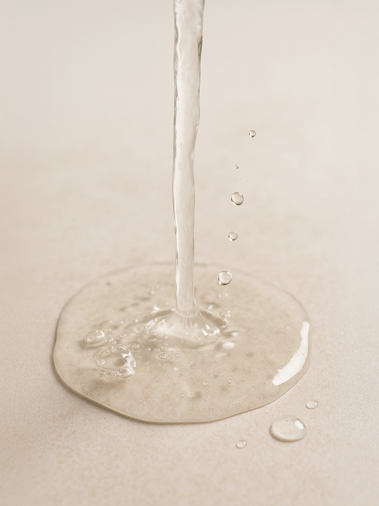 Close-up of a droplet of water on a beige surface Glycolic Acid Liquid Exfoliator