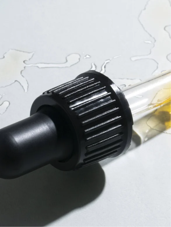 Close-up shot of Suvéra beard oil dropper with golden oil visible inside the pipette