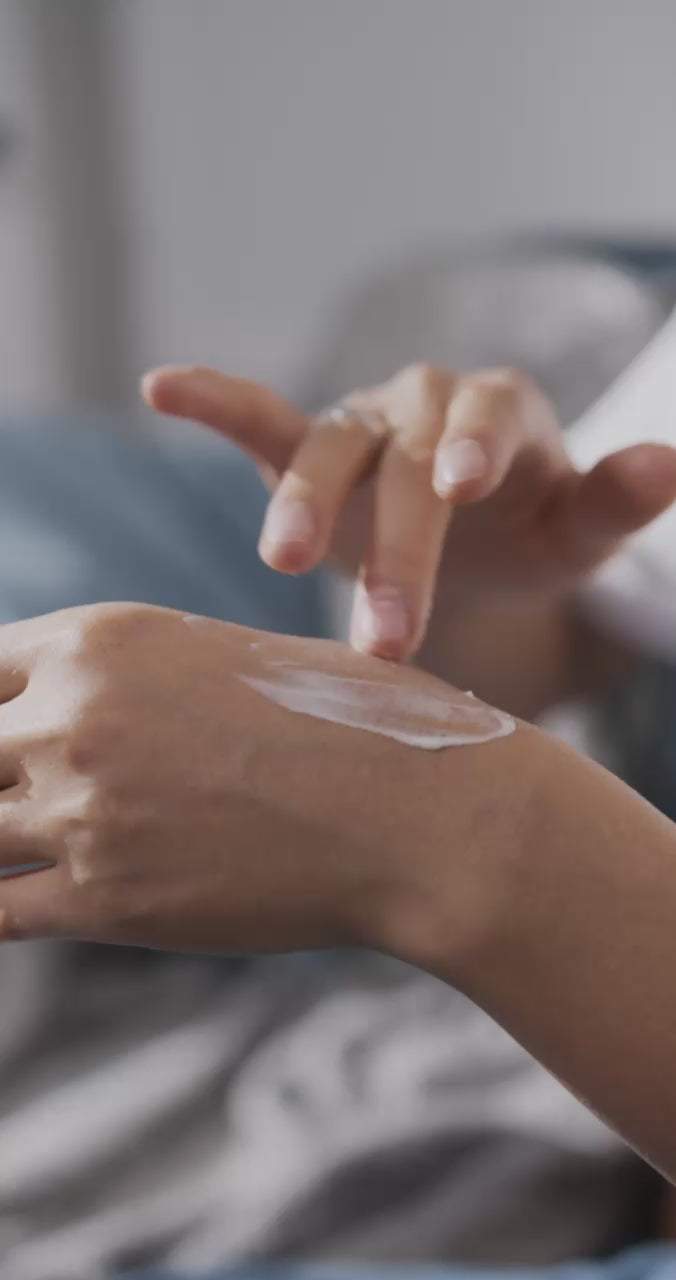 Flat lay of silky cream dollop atop marble disc with citrus accents, pink pepper, cardamom, ginger, sandalwood chips, and wispy vetiver—soft, airy styling.